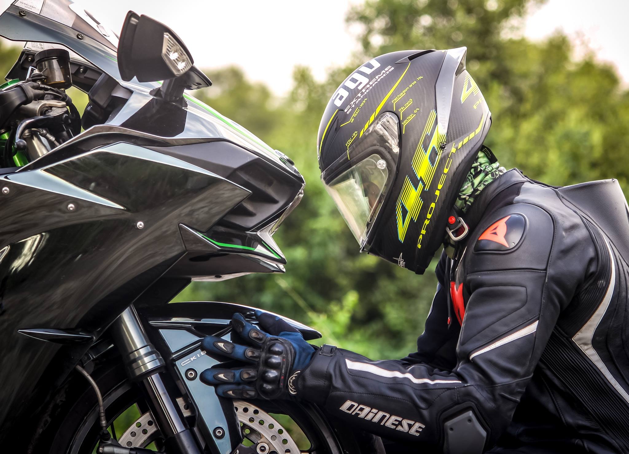 Un motard avec un casque devant une moto noire