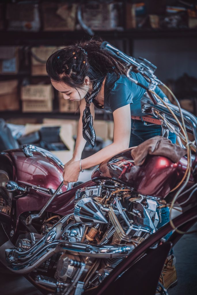 Un femme réparant une moto dans un garage